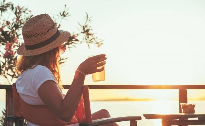 woman sitting holding drink looking at sunset